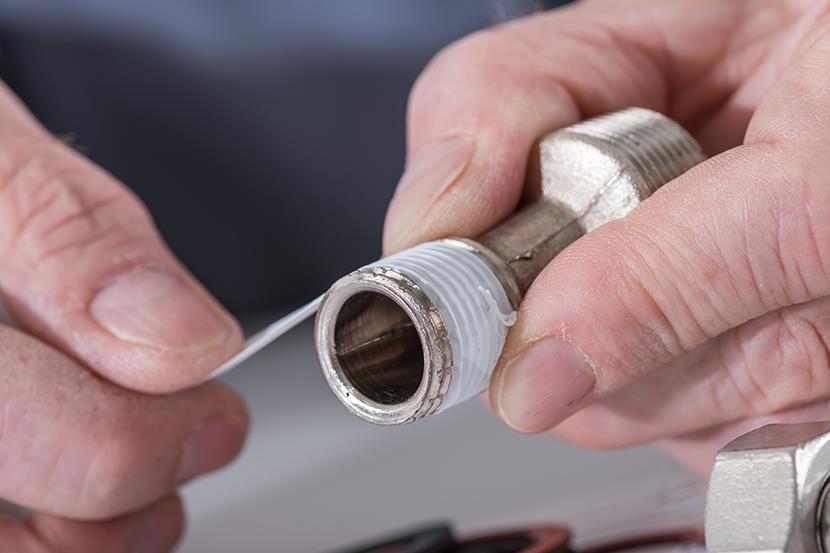 closeup of a person adding teflon tape to a screws threads
