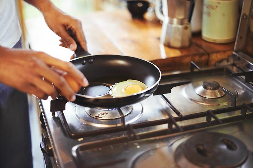 person cracking eggs into a frying pan