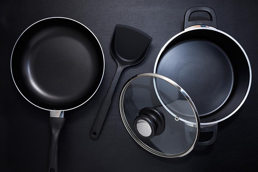 top view of a black frying pan stock pot lid and spatula