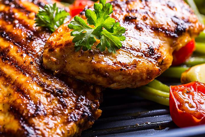 closeup of grilled chicken breasts and herbs