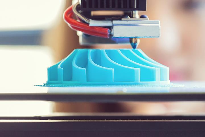 person standing behind close up shot of blue 3d printout