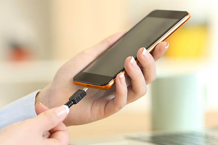 womans hands holding smartphone and charger